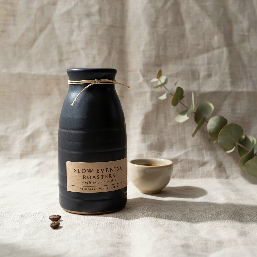 The same coffee bottle edited with Ideogram 4.5 to matte charcoal with the label SLOW EVENING ROASTERS, backdrop and light unchanged